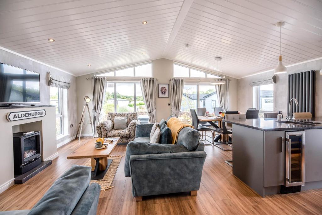 uma sala de estar com sofás, uma cozinha e uma mesa em Marshwiggle, Aldeburgh em Aldeburgh