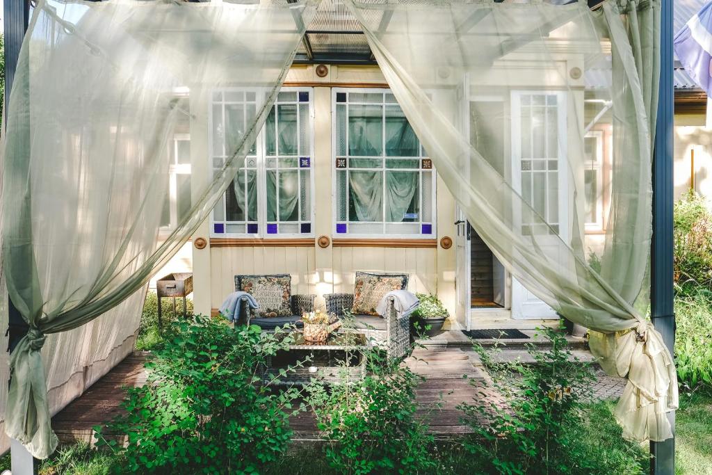 eine abgeschirmte Veranda mit Sofa und Vorhängen in der Unterkunft Villa Irbe in Jūrmala