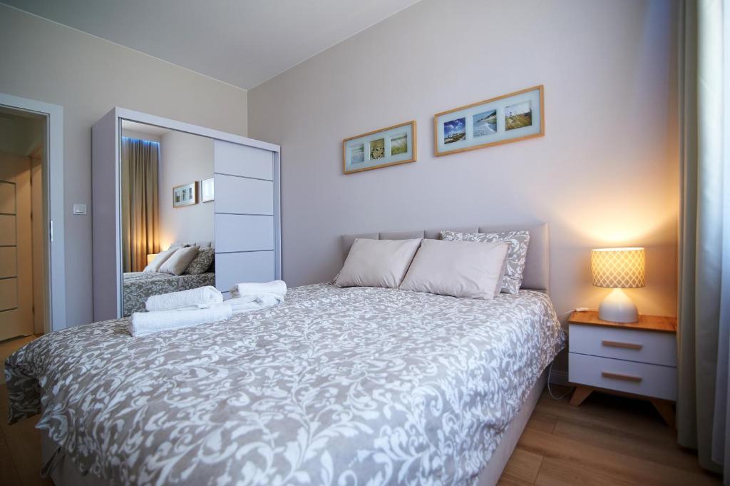 a bedroom with a large bed and a mirror at Apartament z ogródkiem in Uniejow