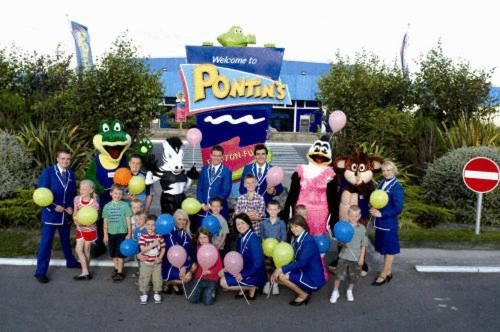 un grupo de niños parados en un estacionamiento con globos en Pontins - Camber Sands Holiday Park, en Camber