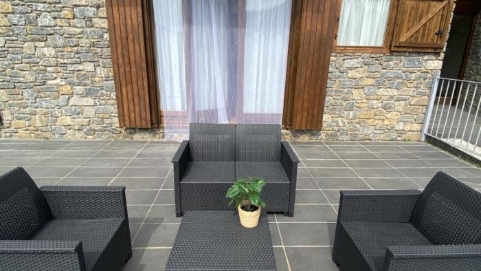 a patio with two black chairs and a potted plant at D01 CABIROL DURRO by IMMOVALL in Durro