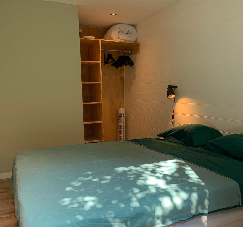 a bedroom with a bed with a green blanket on it at Tinyhouse Scheveningen beach FREE gated parking in Scheveningen