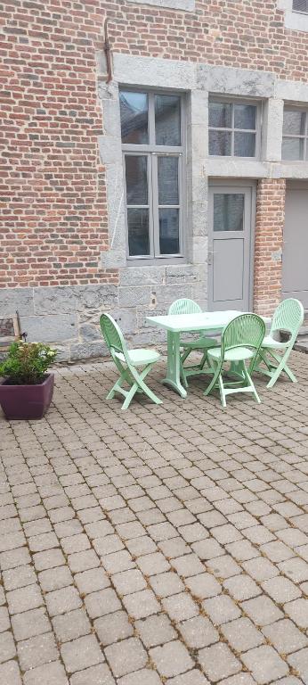 um pátio com uma mesa e cadeiras num edifício de tijolos em APPARTEMENT neuf au centre ville situé au rdc avec terrasse em Givet