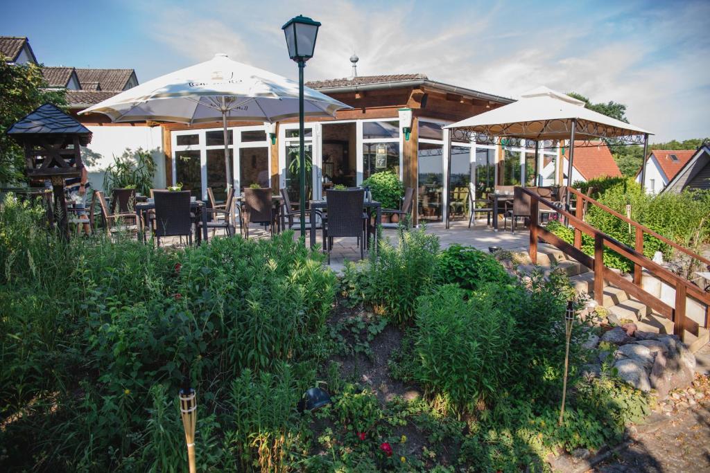 eine Terrasse mit Tischen, Stühlen und Sonnenschirmen in der Unterkunft Landhotel Peters in Canow