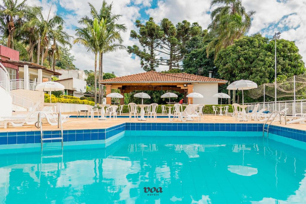 una piscina in un resort con sedie e ombrelloni di VOA Plazza Hotel ad Águas de Lindóia