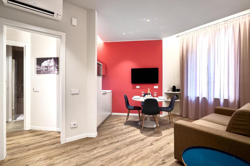 DONATELLO11 Milan apartments في ميلانو: غرفة معيشة مع طاولة وجدار احمر