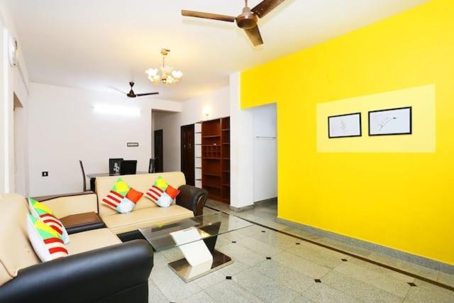 uma sala de estar com um sofá e uma parede amarela em The Solo Apartments Kadavanthra em Ernakulam