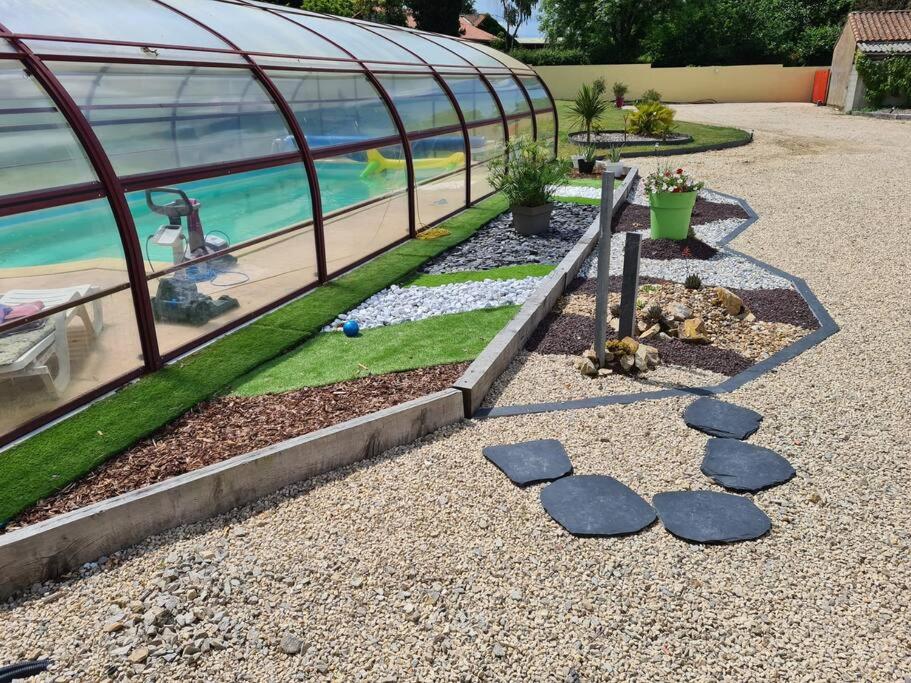 a garden with rocks in front of a greenhouse at Villa Carpe Diem avec piscine et SPA in Saint-Philbert-de-Bouaine