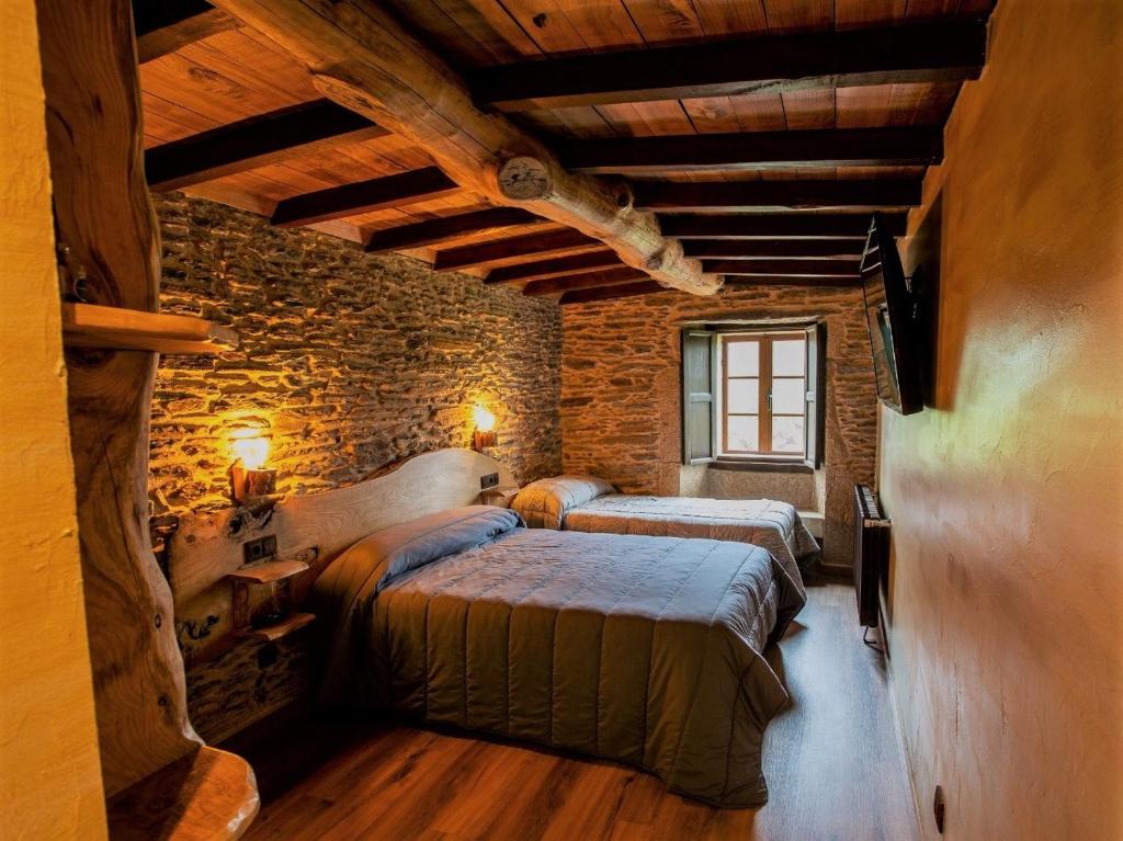 a bedroom with two beds and a brick wall at Fogar de Breogán in Pontevedra