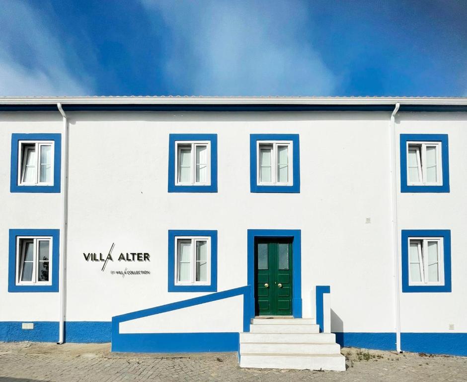 a white building with blue trim and a green door at Villa Alter in Alter do Chão