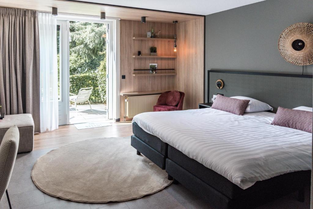 een slaapkamer met een groot bed en een stoel bij Witte Berken Natuurhotel in Epe