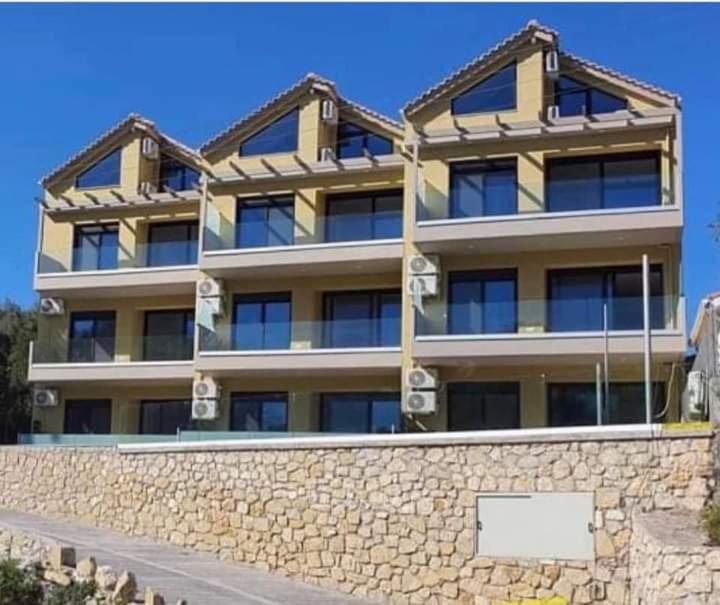 an apartment building with a stone wall and a building at Melivia Luxury Suite in Nikiana