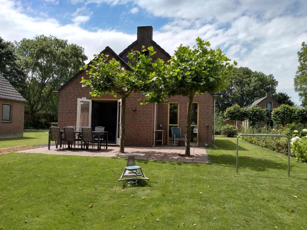 ein Haus mit einem Baum und einer Waage im Hof in der Unterkunft Ellen's home in Ewijk