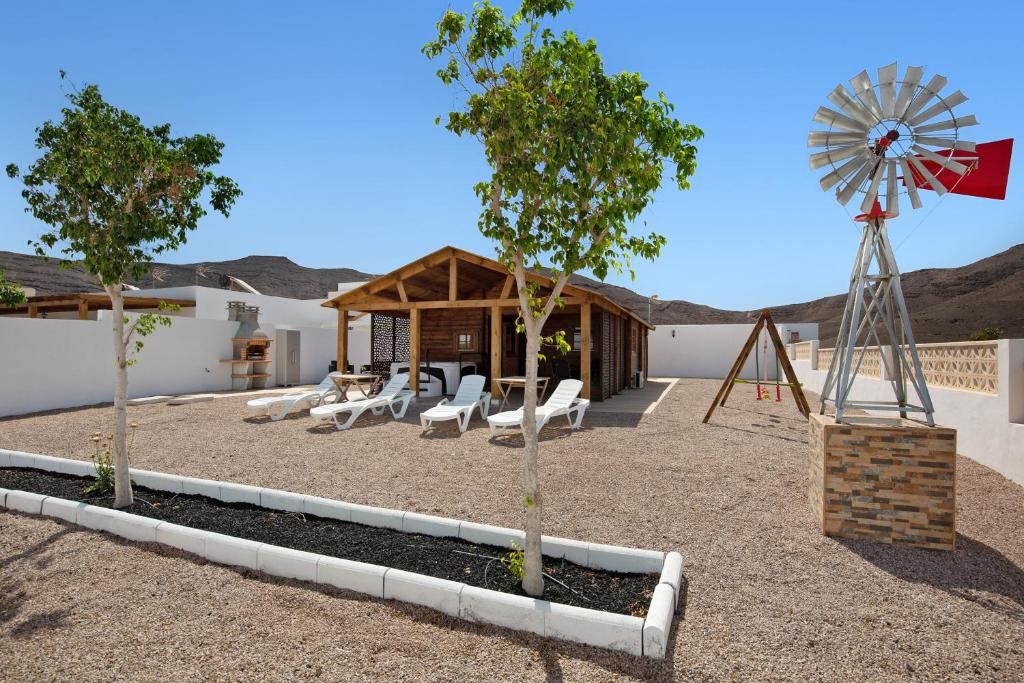 a playground with chairs and a windmill in front of a building at La Cabañita de Javi in Tuineje