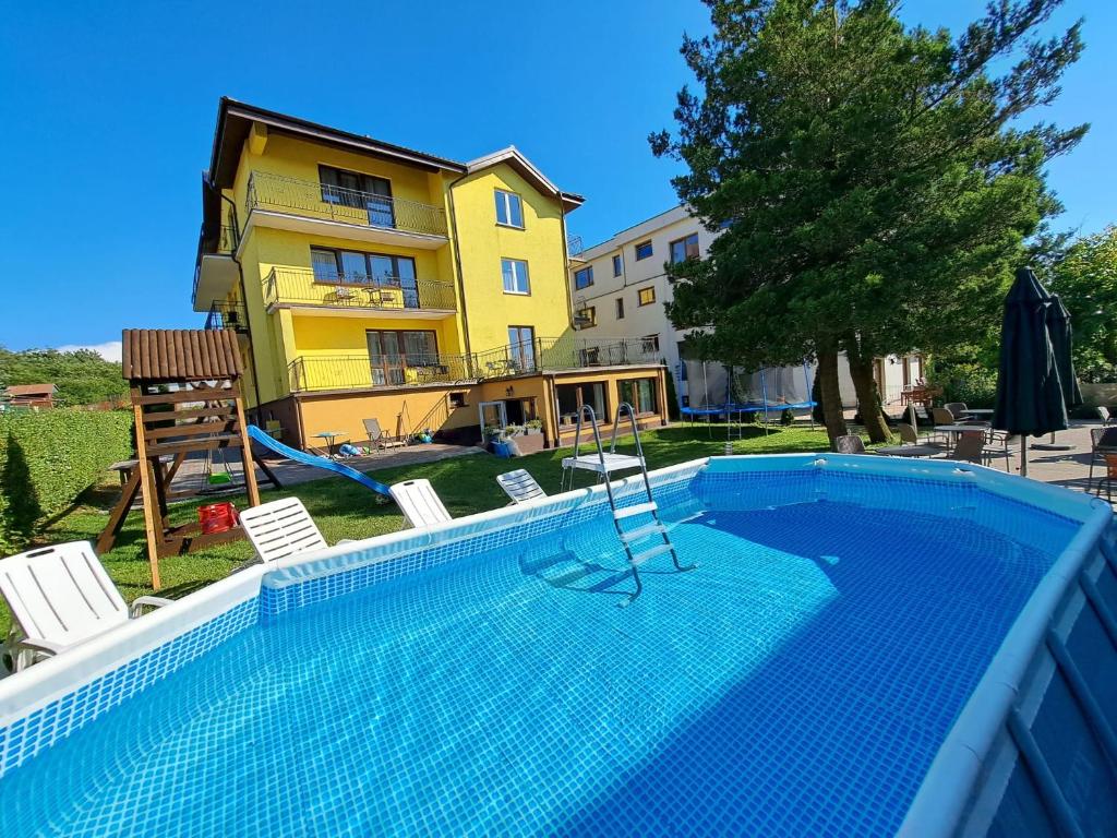 a swimming pool in front of a yellow house at Twoja Przystań Rodzinna in Jastrzębia Góra