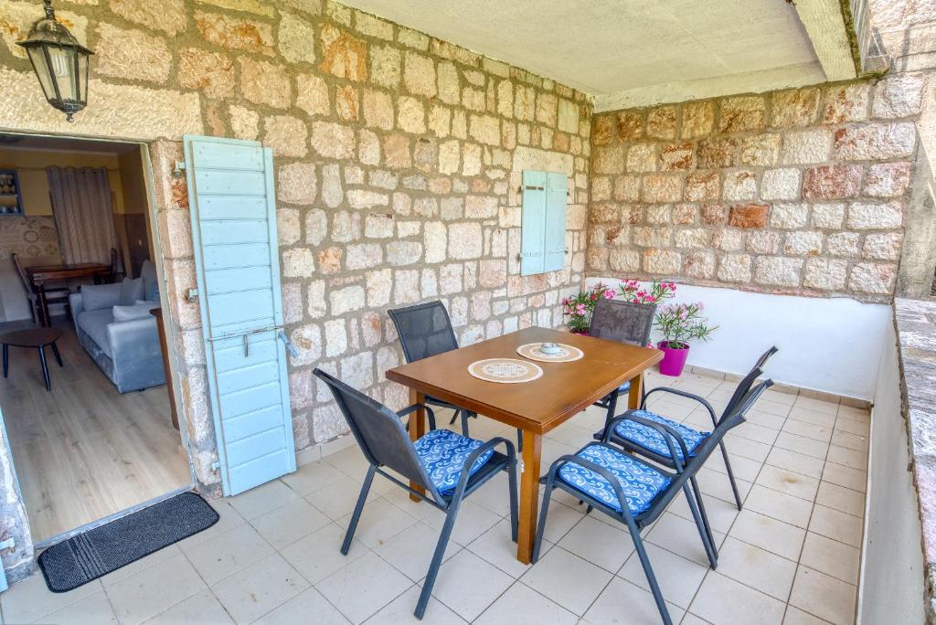 a table and chairs on a patio with a stone wall at Kazanegra Exclusive Apartments in Sveti Stefan