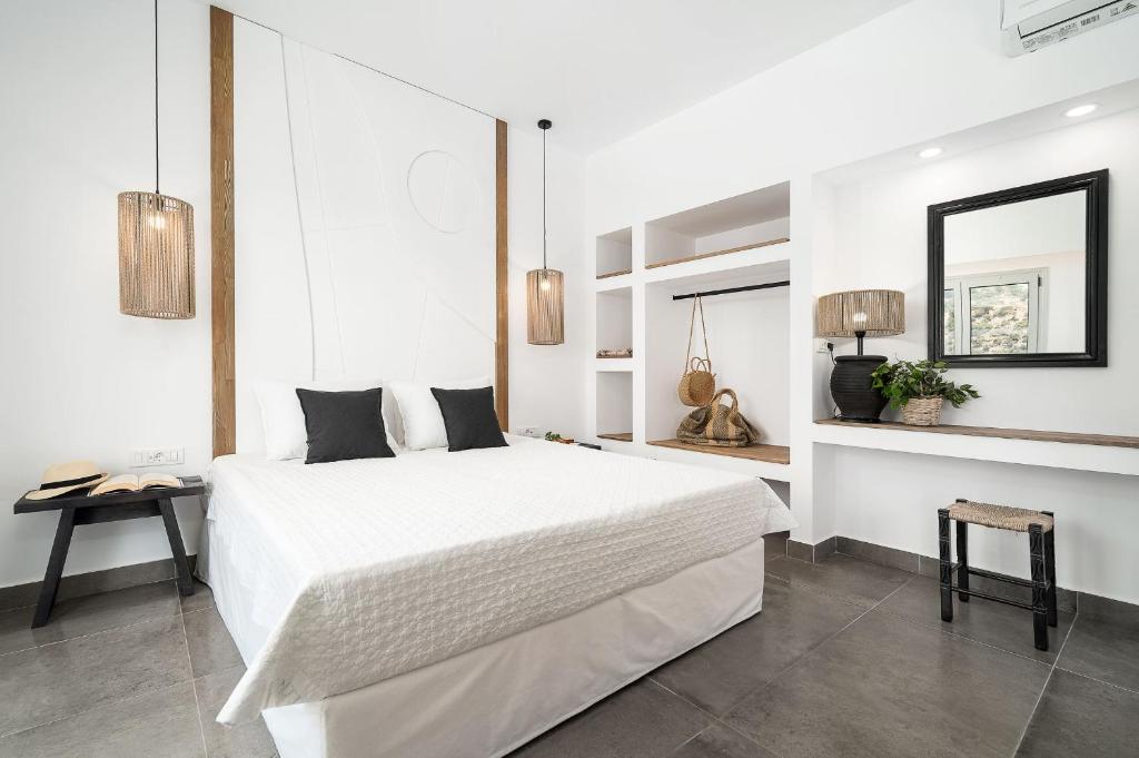 - une chambre blanche avec un grand lit et un miroir dans l'établissement Stella Luxury Apartments, à Agia Galini