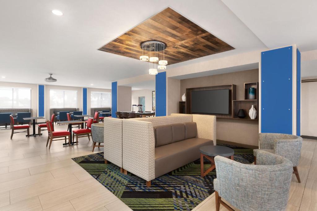 a lobby with a couch and chairs and a tv at Holiday Inn Express Vero Beach-West I-95 by IHG in West Vero Corridor