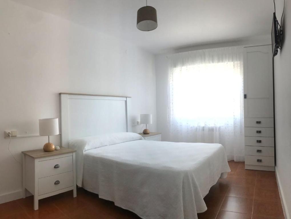 a white bedroom with a white bed and a window at Hostal Casa Enrique in Barres