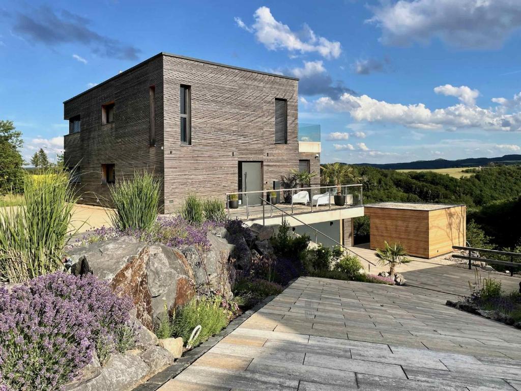 a brick house on a hill with a patio at LuxApart Eifel mit privater Outdoor-Sauna in Harscheid