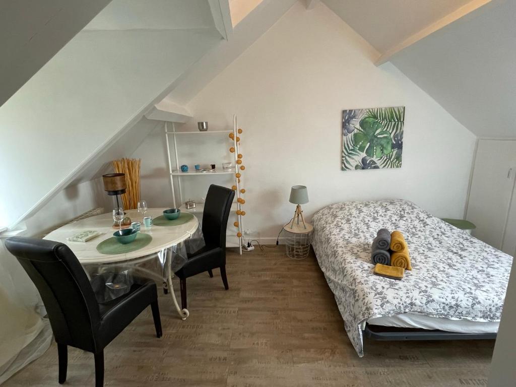 a bedroom with a bed and a table and chairs at Le cocon jaune - Studio en hyper centre in Lamballe