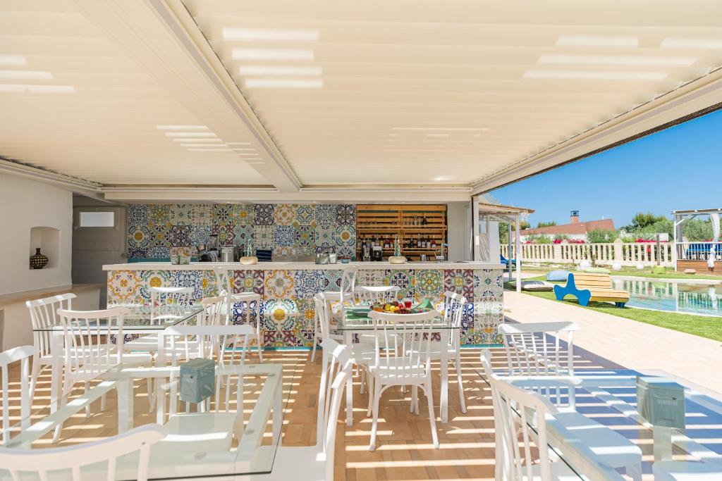 a dining room with white chairs and tables on a patio at Don Leonardo - pool and wellness in Polignano a Mare
