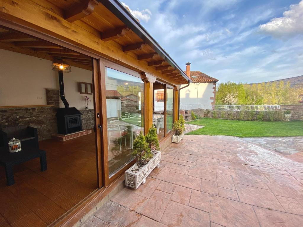 un patio al aire libre con puertas correderas de cristal y chimenea en Casa Rural El Trineo de Campoo - Alto Campoo, en Suano