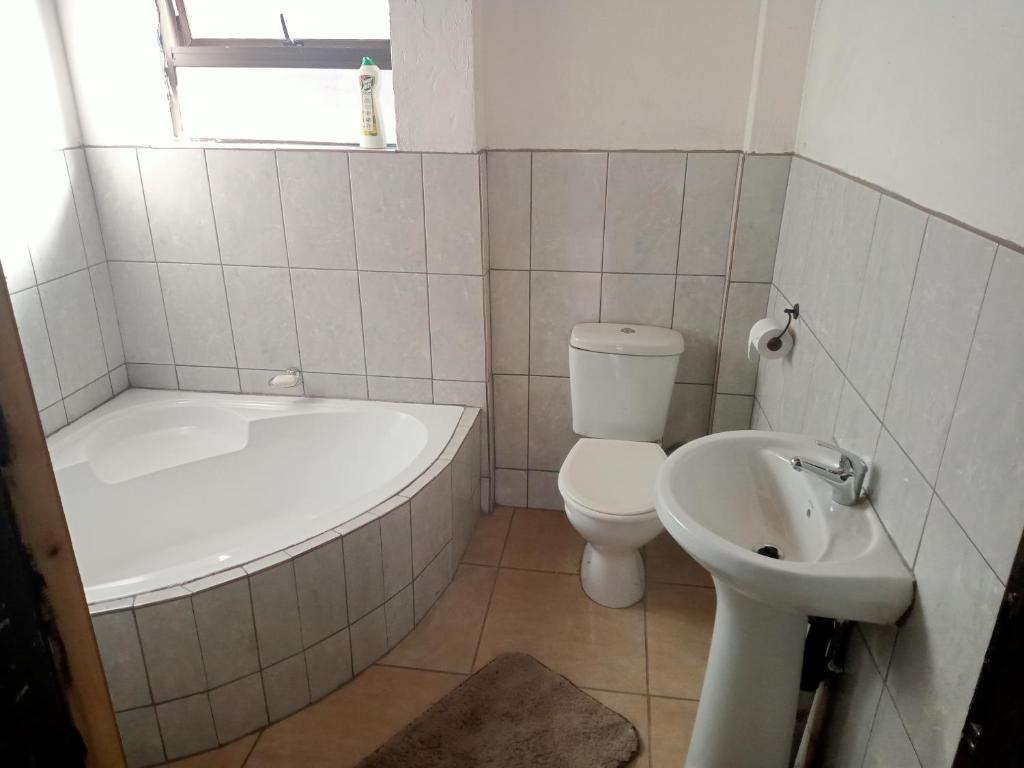 a bathroom with a tub and a toilet and a sink at PARK FRONT LODGE in Polokwane