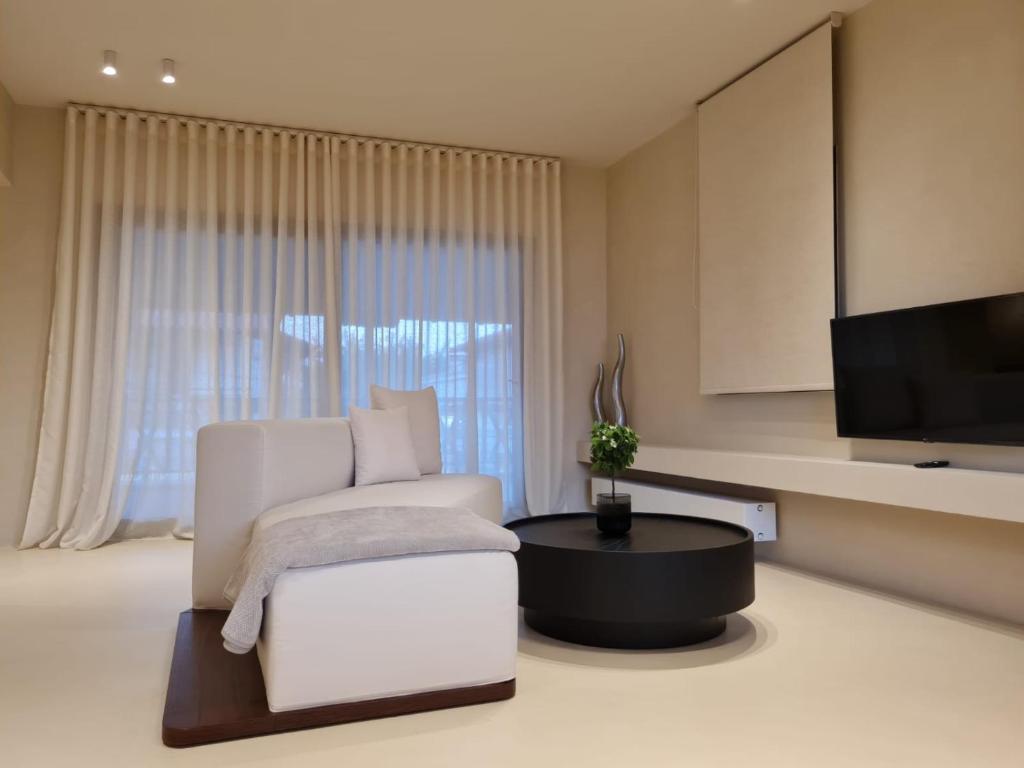 a living room with a white chair and a television at Ammos ikia in Ouranoupoli