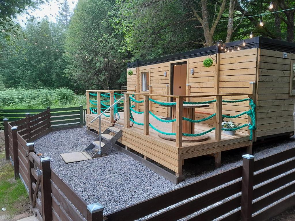 a wooden playground with a slide and a play house at The Cabin, Stronua. A beautiful 1 bedroom cabin. in Fort Augustus