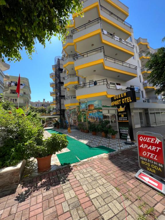 a tall building with a green area in front of it at Alanya Queen Apart Otel in Alanya