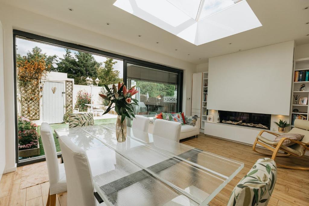 uma sala de jantar com uma mesa de vidro e cadeiras brancas em SWINTON HOUSE - Beautiful 3 Bed House in Harrogate, North Yorkshire em Harrogate