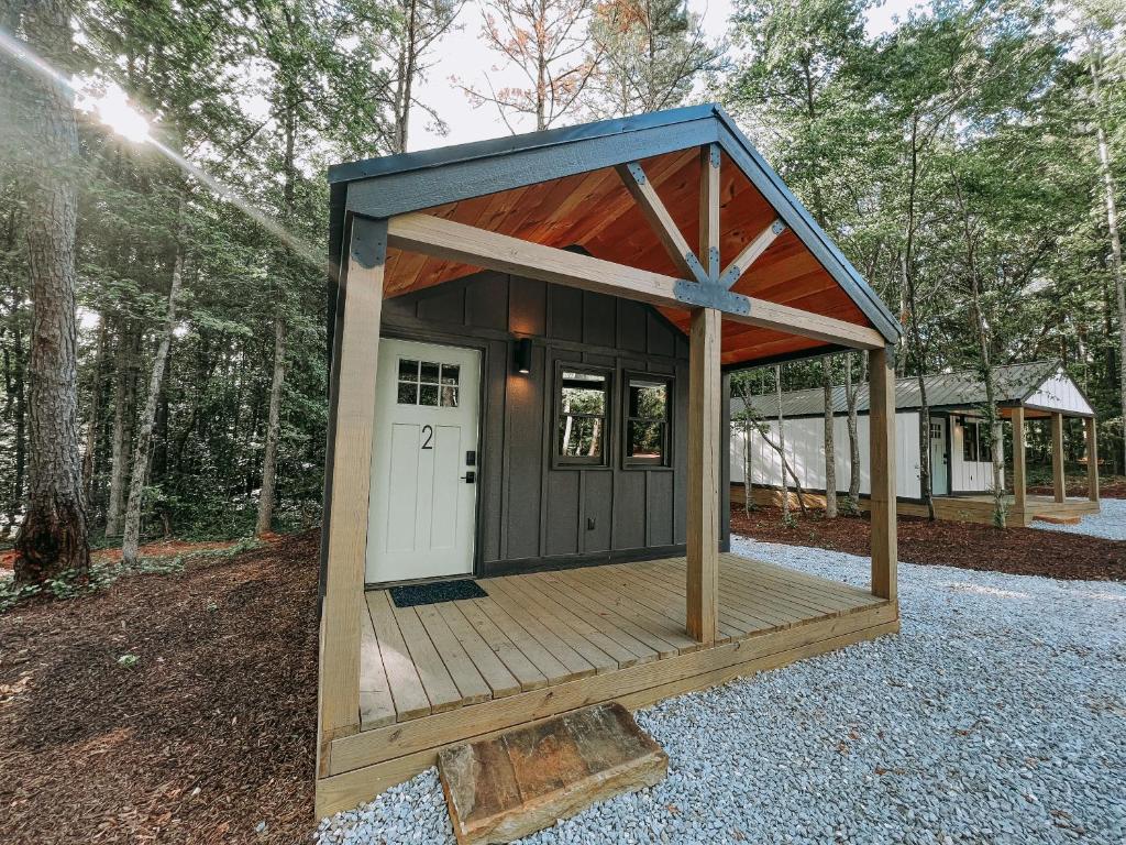 a small cabin with a wooden deck in the woods at Cabin 2 One Bedroom W Kitchen in Hartwell