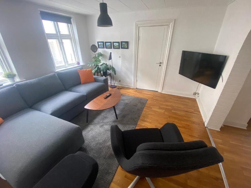 uma sala de estar com um sofá azul e cadeiras em Hyggelig lejlighed i Hjørring centrum em Hjørring