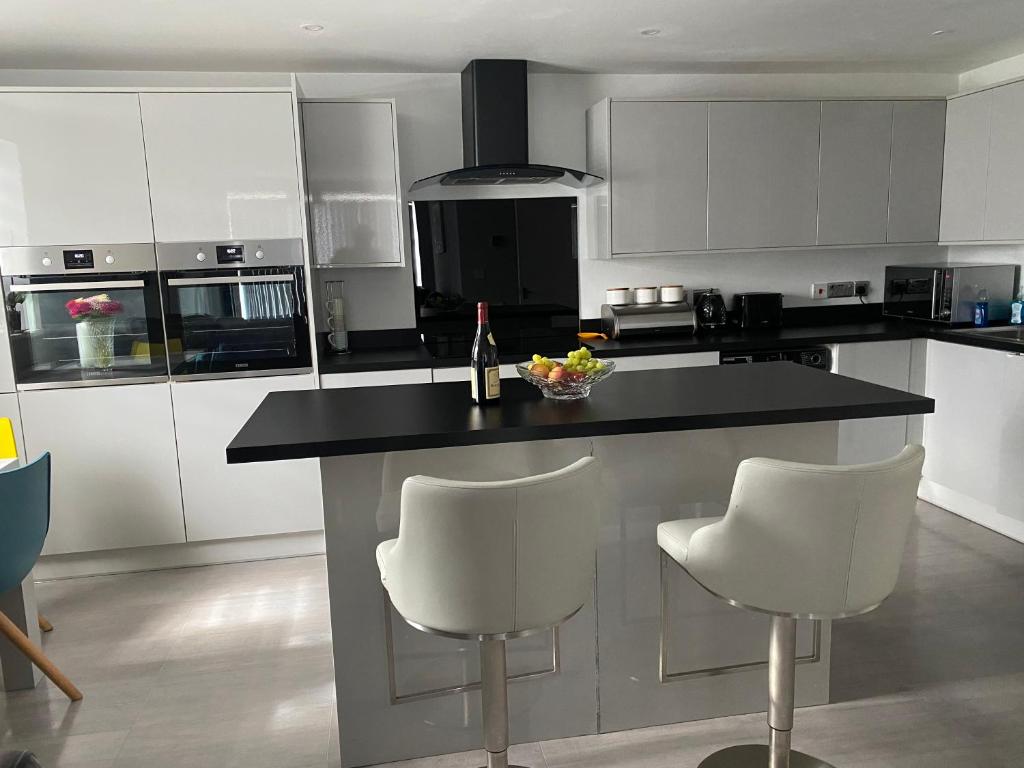 a kitchen with white cabinets and a black counter top at Modern 2 bedrooms fully equipped Apartment with garden, Free Parking, Free Wifi in Dagenham