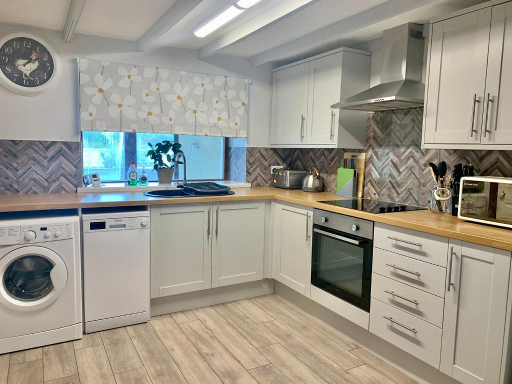 a kitchen with white cabinets and a washer and dryer at Bracknell Cottage in Freystrop