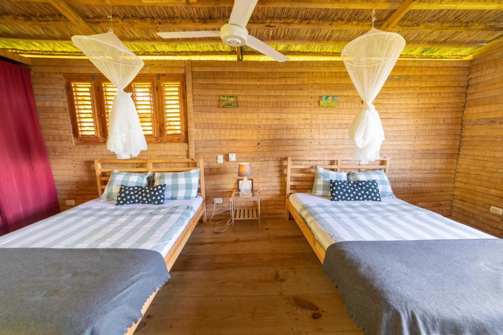 two beds in a room with wooden walls at Hacienda Cocuyo in Monte Rojo