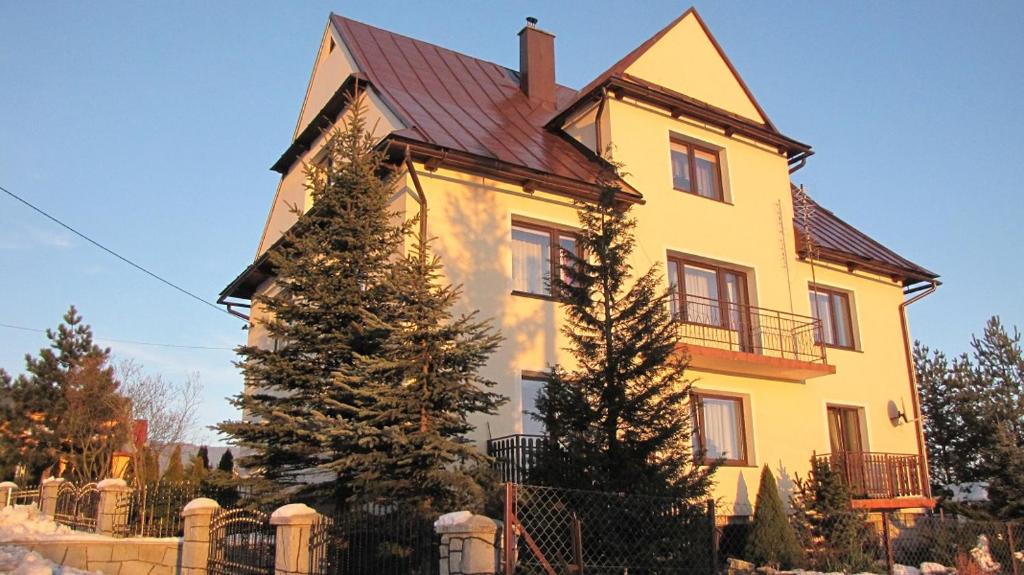 een groot geel huis met een boom ervoor bij U Wojtaszka in Mizerna