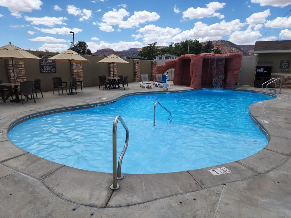 a large swimming pool at a resort with tables and chairs at Comfort Suites Kanab National Park Area in Kanab