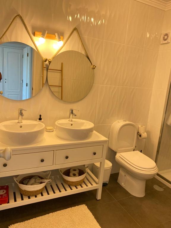 y baño con 2 lavabos, aseo y espejo. en OndasDaVagueira - T2 em condomínio com piscina en Gafanha da Boa Hora