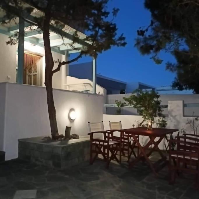 a patio with a table and chairs and a tree at paros seaside experience in Aliki