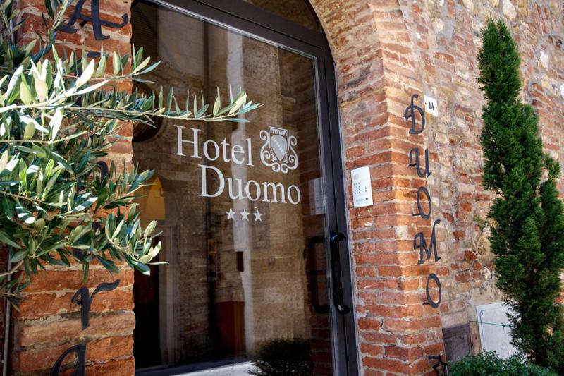 un cartello Hotel Duncano sul lato di un edificio in mattoni di Albergo Duomo a Montepulciano