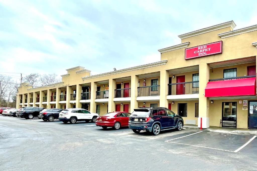 un gran edificio con coches estacionados en un estacionamiento en Red Carpet Inn Philadelphia Airport en Lester