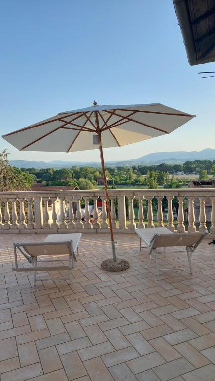 a patio with two benches and an umbrella at La casa del Mago camere e appartamenti in Pissignano