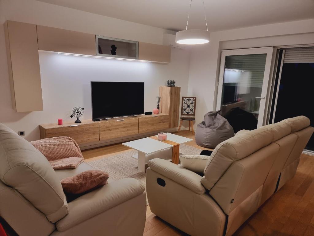a living room with two chairs and a flat screen tv at Skitnica Prestige in Koprivnica