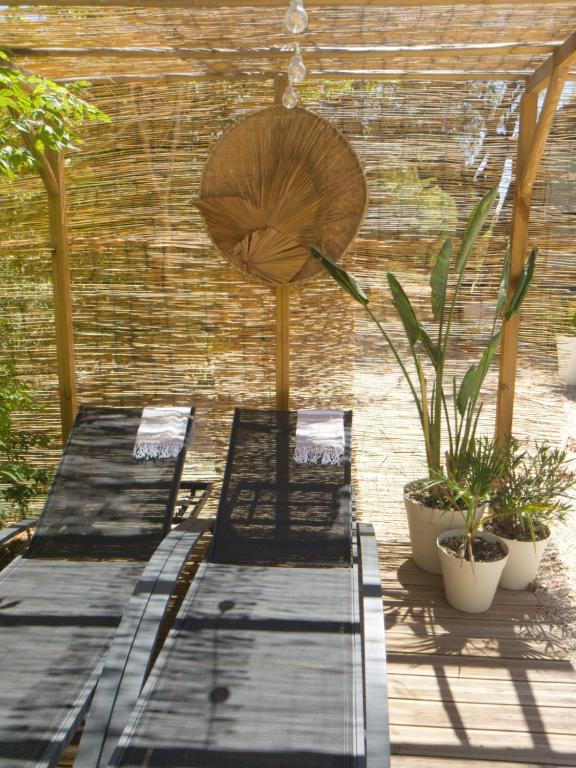2 bancs assis sur un patio orné de plantes dans l'établissement Magnifique Cabanon avec jacuzzi et sauna, à Aubagne