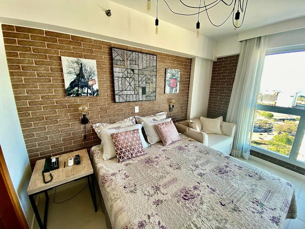 a bedroom with a brick wall and a large bed at Saint Moritz Flat Particular com Garagem, Estilo Provençal no Coração de Brasília in Brasília