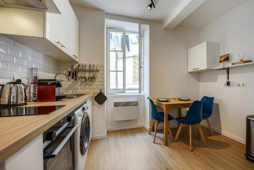 a kitchen with a table and blue chairs at Nice and modern flat at the heart of Panier in Marseille - Welkeys in Marseille