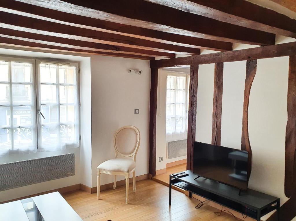 salon z telewizorem i krzesłem w obiekcie EXIGEHOME-Studio Cosy à 2 pas du Chateau de Versailles w Wersalu