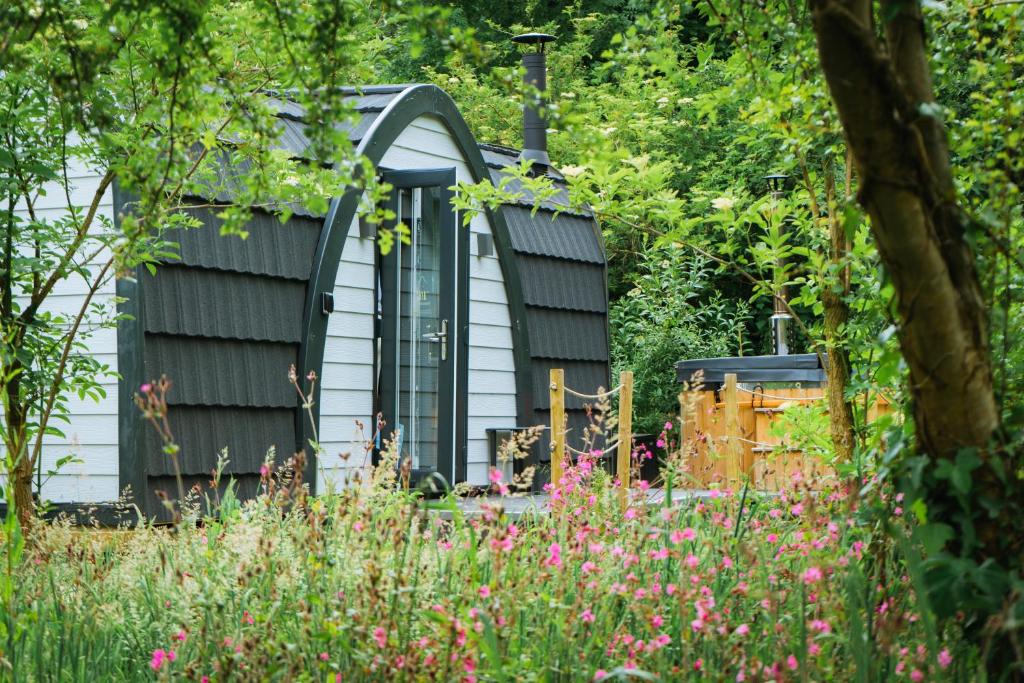einen Garten mit einem Haus im Hintergrund in der Unterkunft Emlyn's Coppice - Luxury Woodland Glamping in Holywell